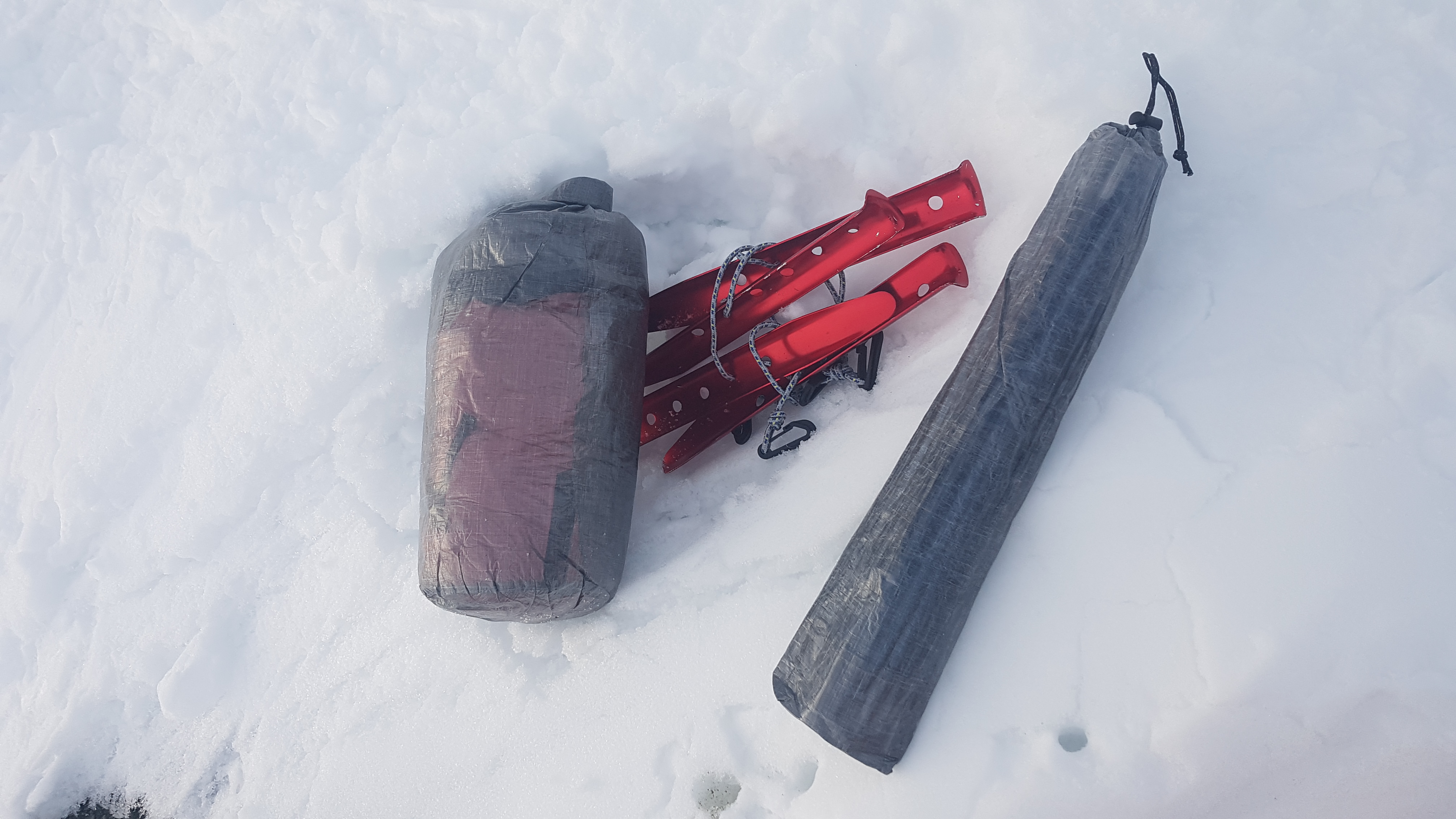 Zusammengepackt: Zelt, Stangen und Schneeheringe