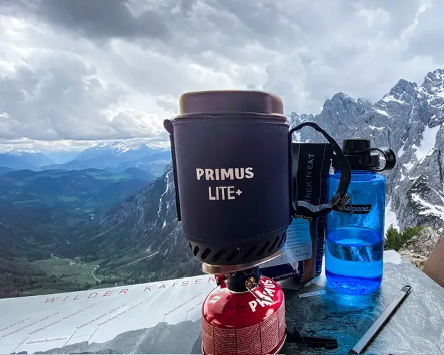 Der LITE+ des Testers vor einer Bergkulisse, daneben eine Literflasche von Nalgene und eine Tüte Instantnahrung