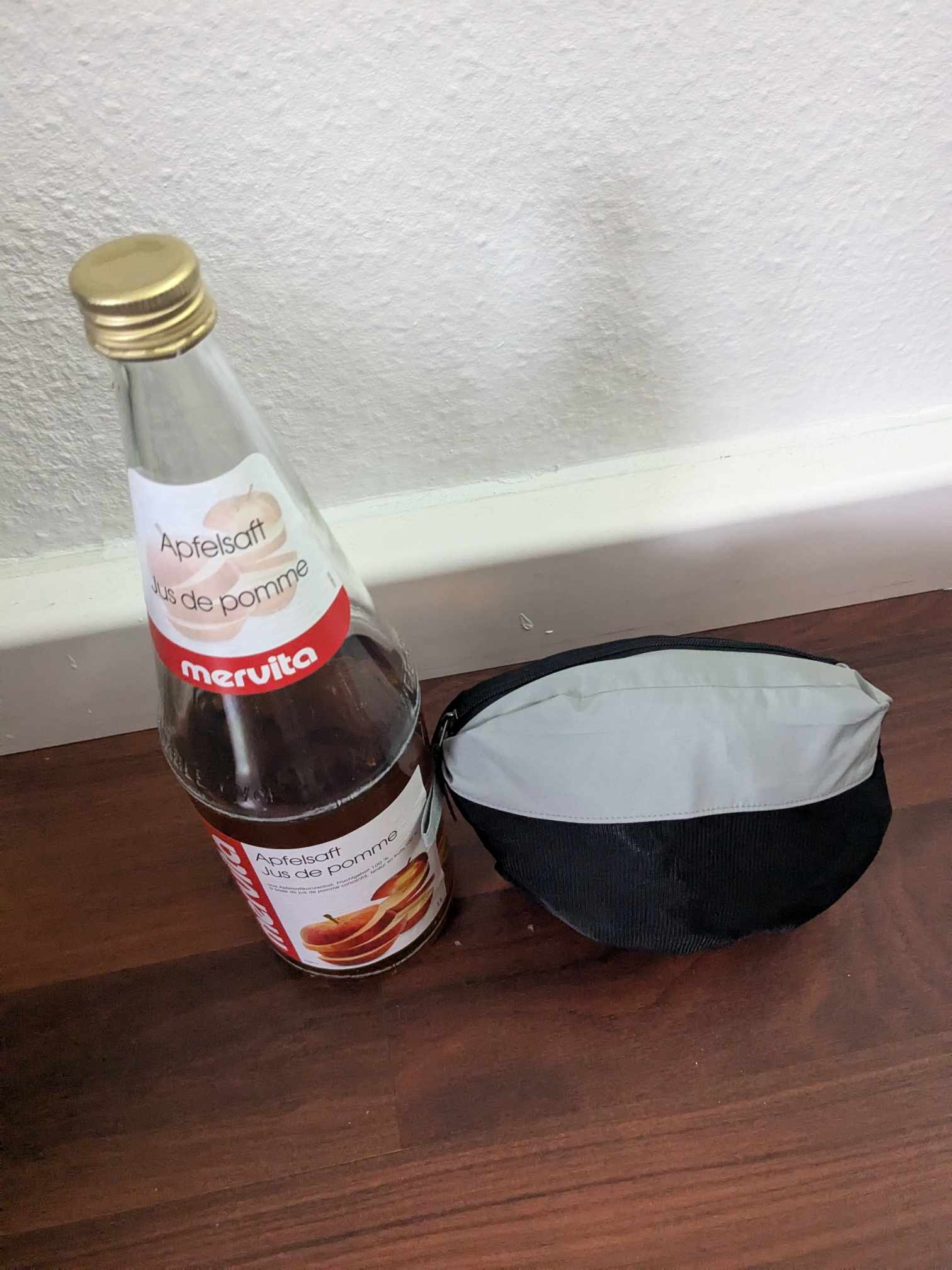 Man sieht die komprimierte Jacke im Vergleich mit einer 1l Flasche 