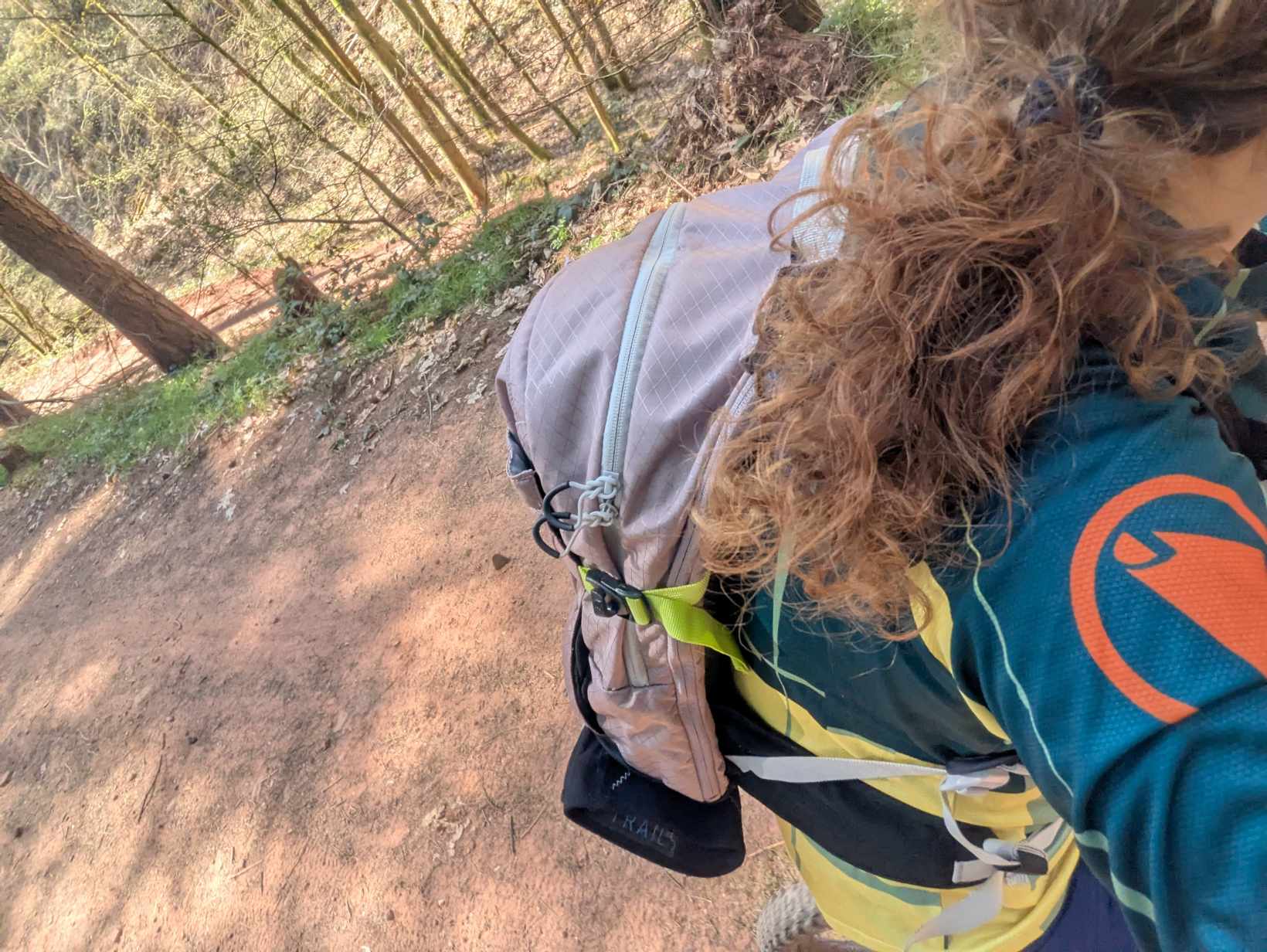 Man sieht jemanden mit Rucksack auf dem Rücken auf dem Fahrrad von der Seite 