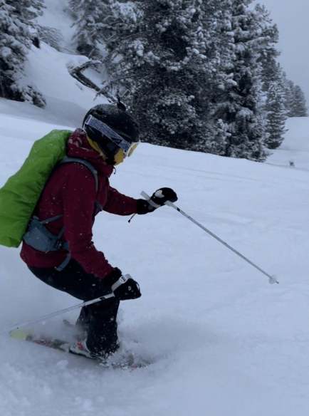Rucksack mit grüner Regenhülle im schnee
