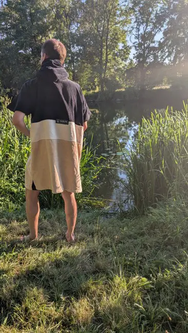 Rückseite des Ponchos mit Händen in der Bauchtasche