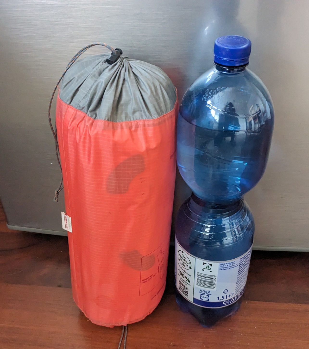 Die Matte ist im Größenvergleich mit einer 1,5l Flasche zu sehen, das Kissen ist mit in der Hülle drin. Die Matte ist etwas kleiner als die Flasche