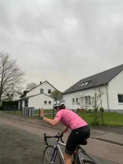 Es ist eine Kombination aus Hose und Trikot zu sehen, die von einer Frau auf einem Rennrad getragen wird